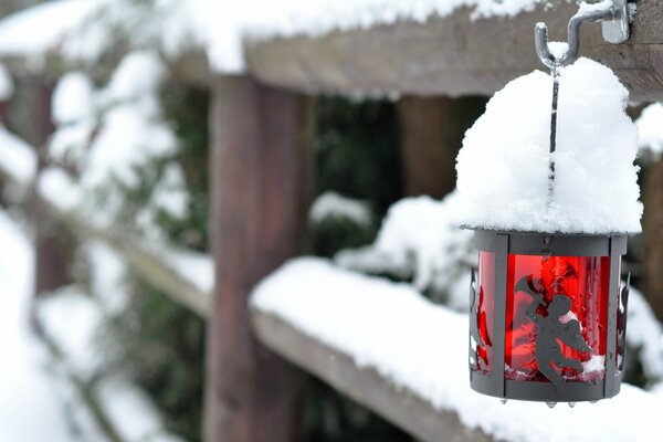 Lantern with an angel on a snow-covered fence