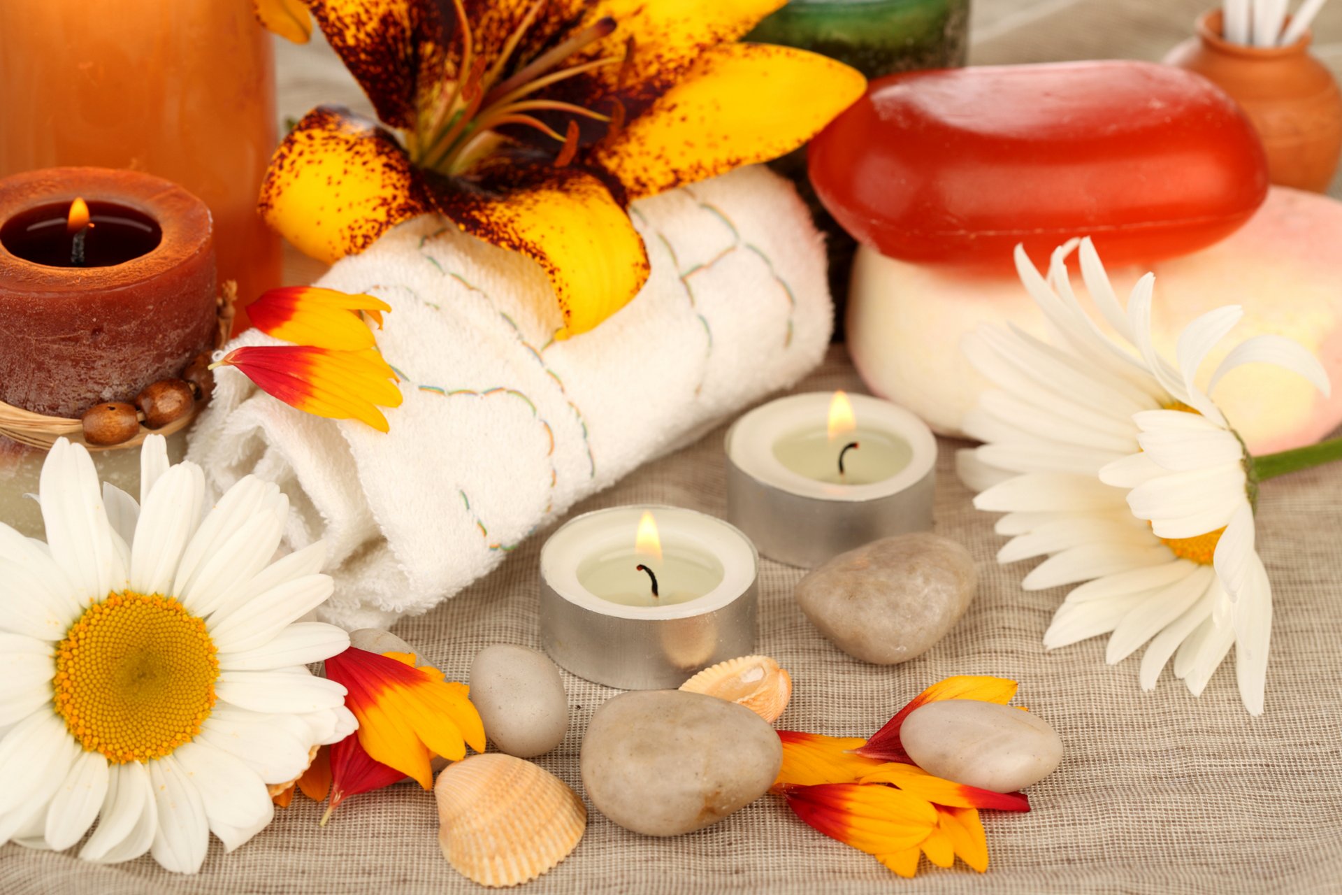 candele pietre conchiglie asciugamani fiori petali margherite sapone spa