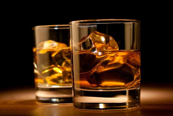 Imagen sobre la mesa hay dos vasos con hielo y whisky