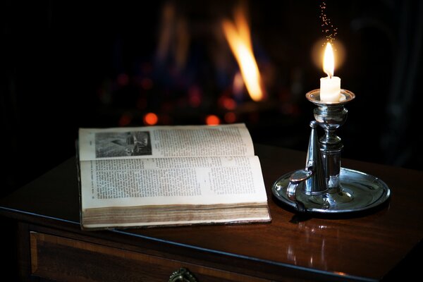 Sul comodino c è una candela in un candelabro e un libro aperto