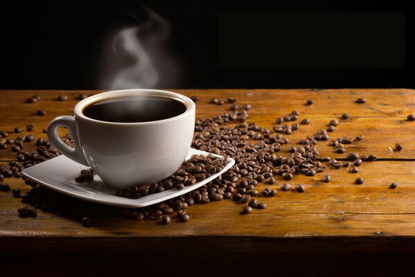 Tasse mit dampfendem Kaffee unter Kaffeebohnen