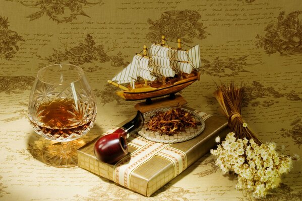 A picture on the table a gift a pipe a ship flowers and a glass