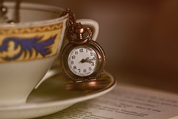 Taza con reloj de bolsillo en la mesa