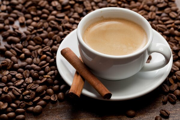 Café dans une tasse de couleur blanche et cannelle dans une soucoupe