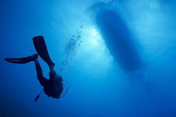 I subacquei nuotano in profondità sotto la barca