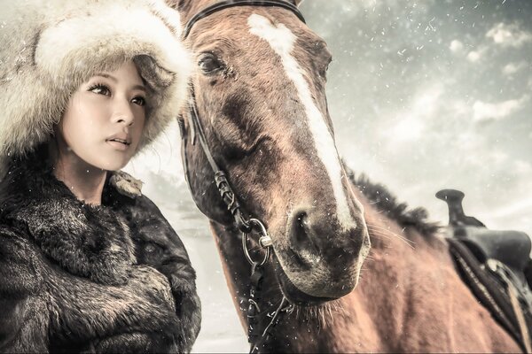 Fille dans un manteau de fourrure et un chapeau avec un cheval