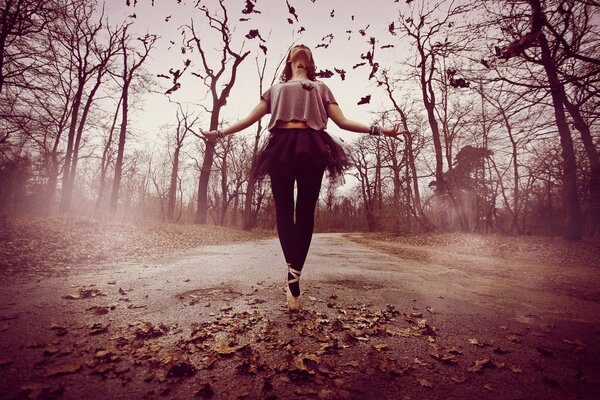 Girl dancing on the road surrounded by leaves