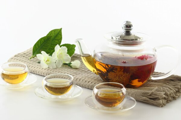 Teapot with bowls filled with tea. Next to the flower