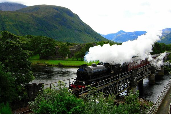 Locomotive à vapeur traverse le pont sur le fond de la montagne