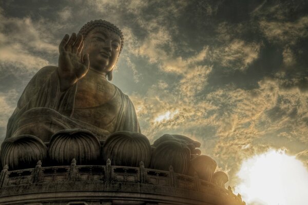 Statua di Buddha su uno sfondo di cielo, sole, nuvole