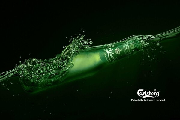 Бутылка пива carlsberg которая плавает в темной воде