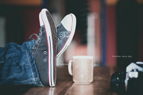 A wooden table with a camera and sneakers on it