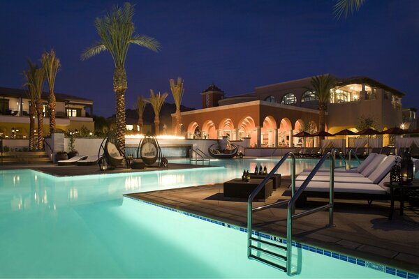 House with swimming pools and sun beds at night