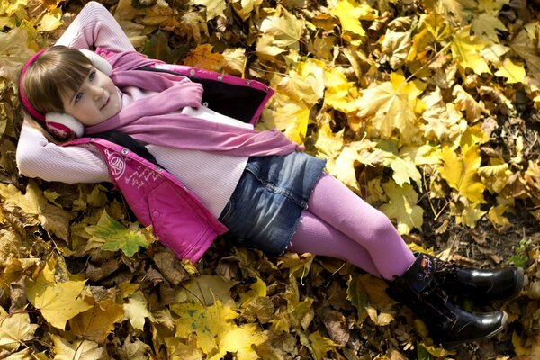 Fille en robe rose repose sur les feuilles jaunes