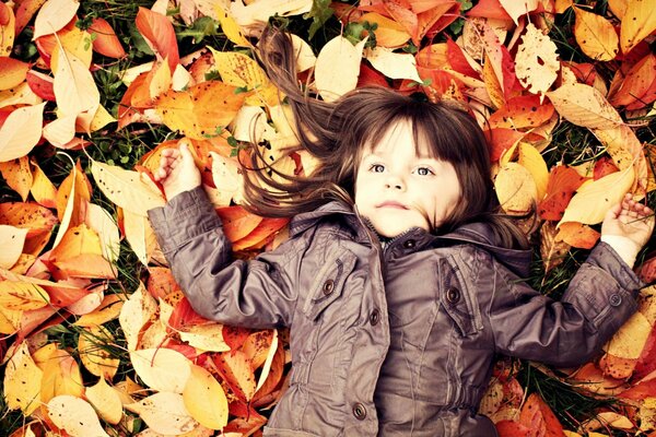 A girl likes a carpet made of fallen leaves