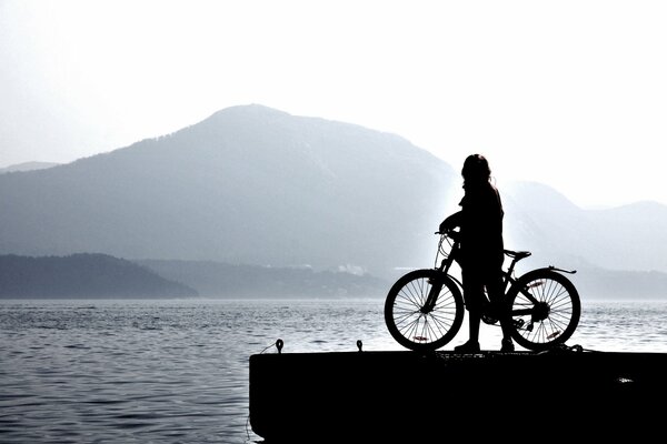 A man on a bicycle near a pond