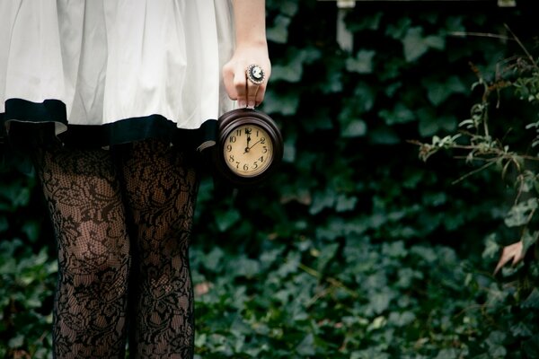 Image d une jeune fille en robe blanche avec une horloge à la main