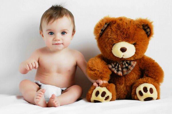 A baby in a diaper is sitting with a toy