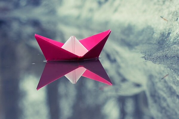 Floating paper, pink boat in reflective winter water