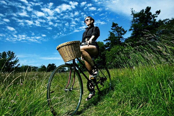 Fille avec un panier sur un vélo dans la lisière de la forêt