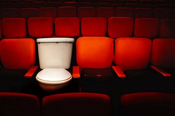 Toilet bowl next to the red seats