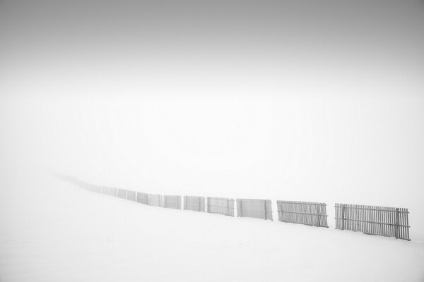 A long fence in a deep fog