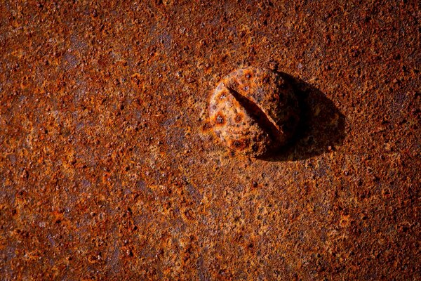 Il bullone metallico arrugginito rosso si trova