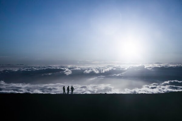 People on the mountain are on the same level with the clouds under the rays of the sun