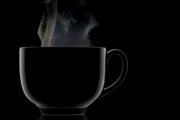 Tasse noire à partir de laquelle va la vapeur sur fond noir