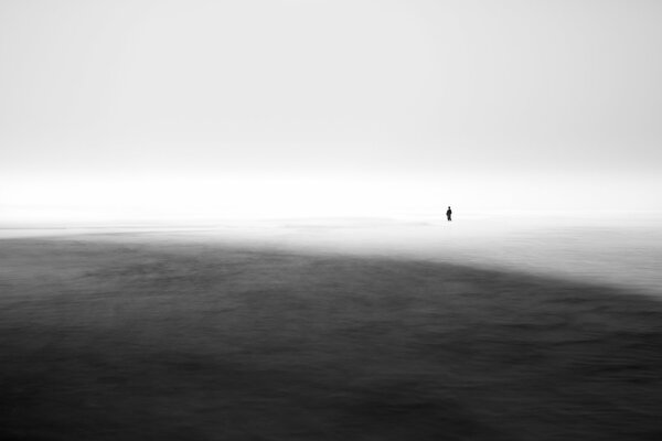 El hombre de pie en el mar en la niebla