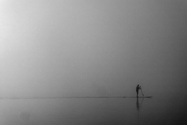 A man in a fog engaged in sapsurfing at sea