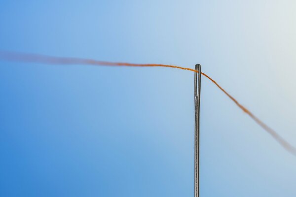 A thread in a needle on a blue background