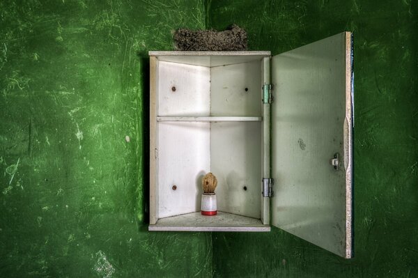 Against the background of a green wall, a bathroom cabinet with shaving accessories