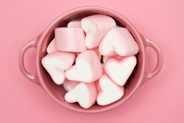 Marshmallows in the shape of hearts are laid out in a cup