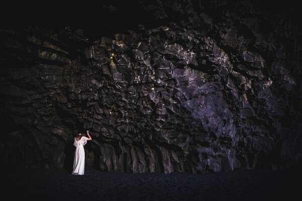 Mädchen im weißen Kleid lehnte sich an einen Felsen