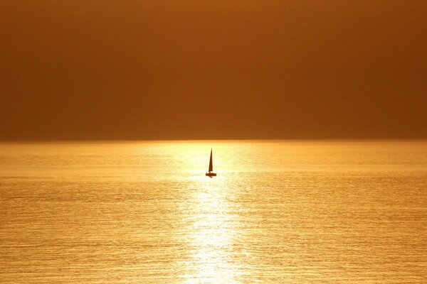 Einsames Segelboot im Meer bei Sonnenuntergang