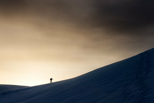 A man walking uphill against a gloomy sky