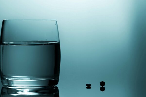 A glass of water with pills on blue