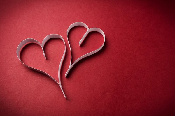 Two paper hearts on a red background