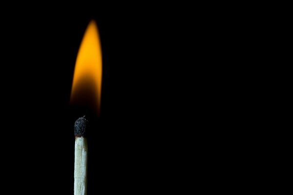 A burning candle on a black background