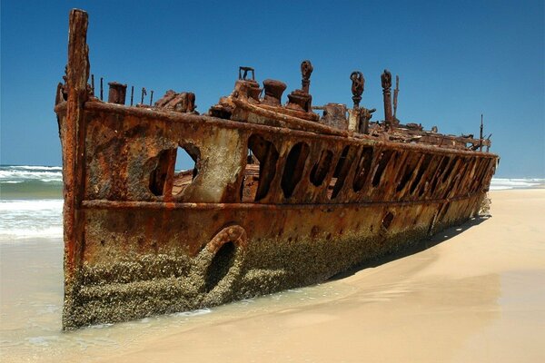 Carcassa arrugginita della nave nella sabbia