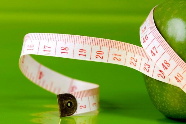 A centimeter tape measures a green apple