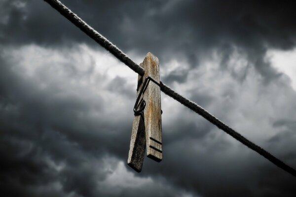 Clothespin on a rope against the background of gloomy clouds