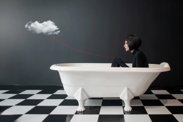 A girl in the bathroom holds a cloud by a red thread