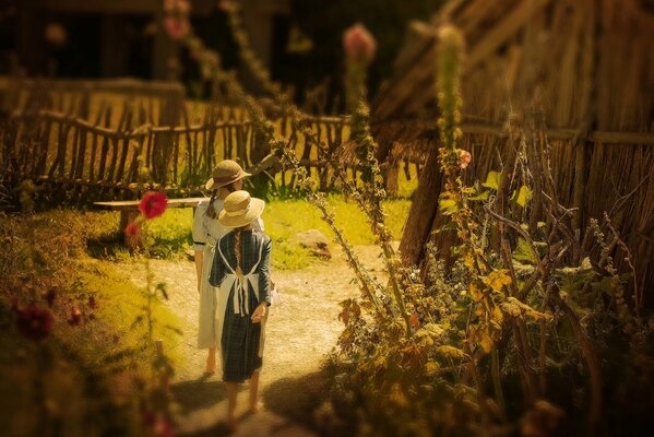 Village girls in hats are walking along the path