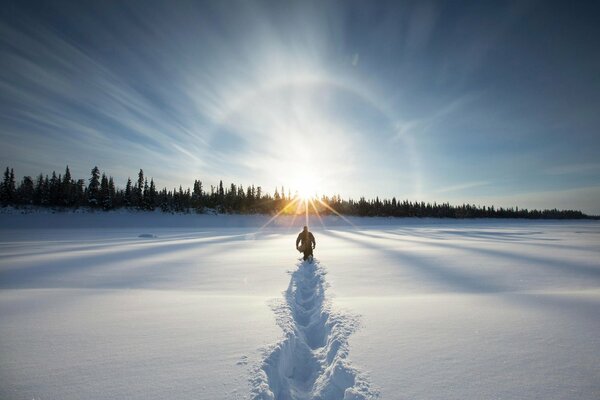 Le voyageur va à travers la neige au soleil