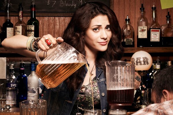 Hermosa chica trata de cerveza en el Bar