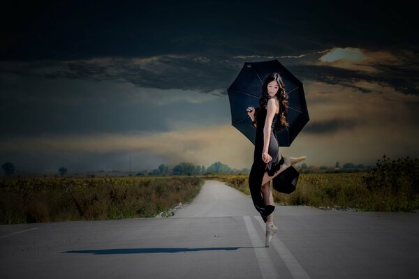 Ballerina with an umbrella on the road