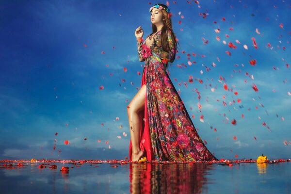 Fille avec des pétales de fleurs en rouge sur l eau