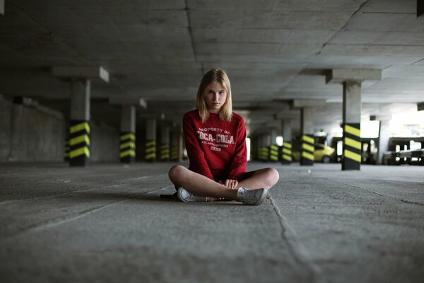 Mädchen sitzt auf dem Asphalt auf dem Parkplatz